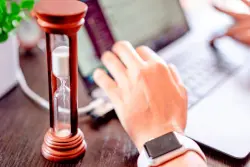 Mano sosteniendo un reloj de arena sobre un calendario con la fecha 2026, ilustrando la gestión del tiempo y las horas extra en Colombia